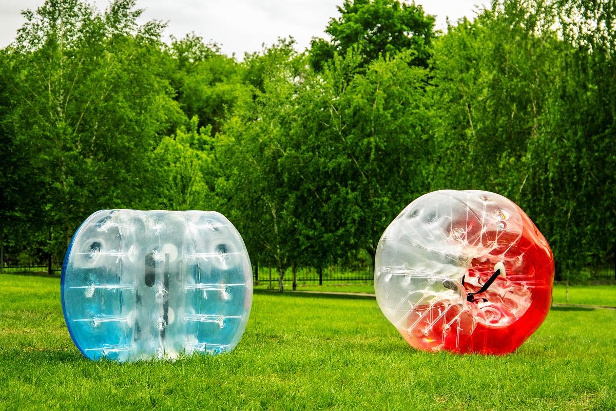 Two Zorbing Balloon on the summer lawn. inflatable zorb ball outdoor. Leisure activity concept with copy space.