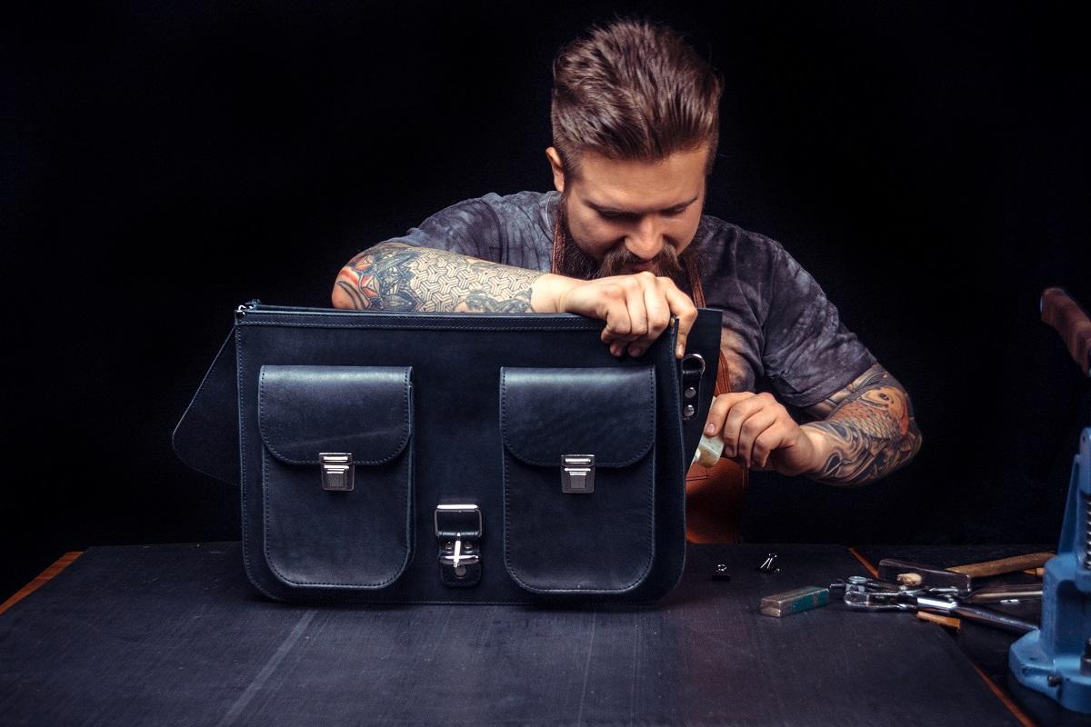 Craftsman professionally making black expensive leather briefcase