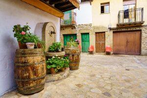 Old village with barrels with plants and flowers in the street, Sequeros, Salamanca. Stone And Brick