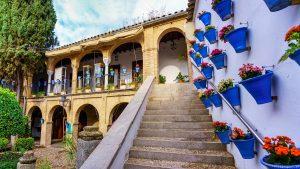 Patio with flower pots and stairs to arcades with arched doors. Cordova. Wonderful Arches