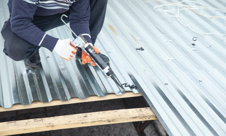 Worker using glue gun with adhesive to fix the metal steel on the roof. Best Adhesives for Stainless Steel.