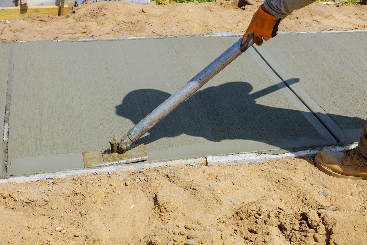 Worker plastering the concrete cement during construction contractor using a float to sidewalk. What Is Concrete Resurfacing.