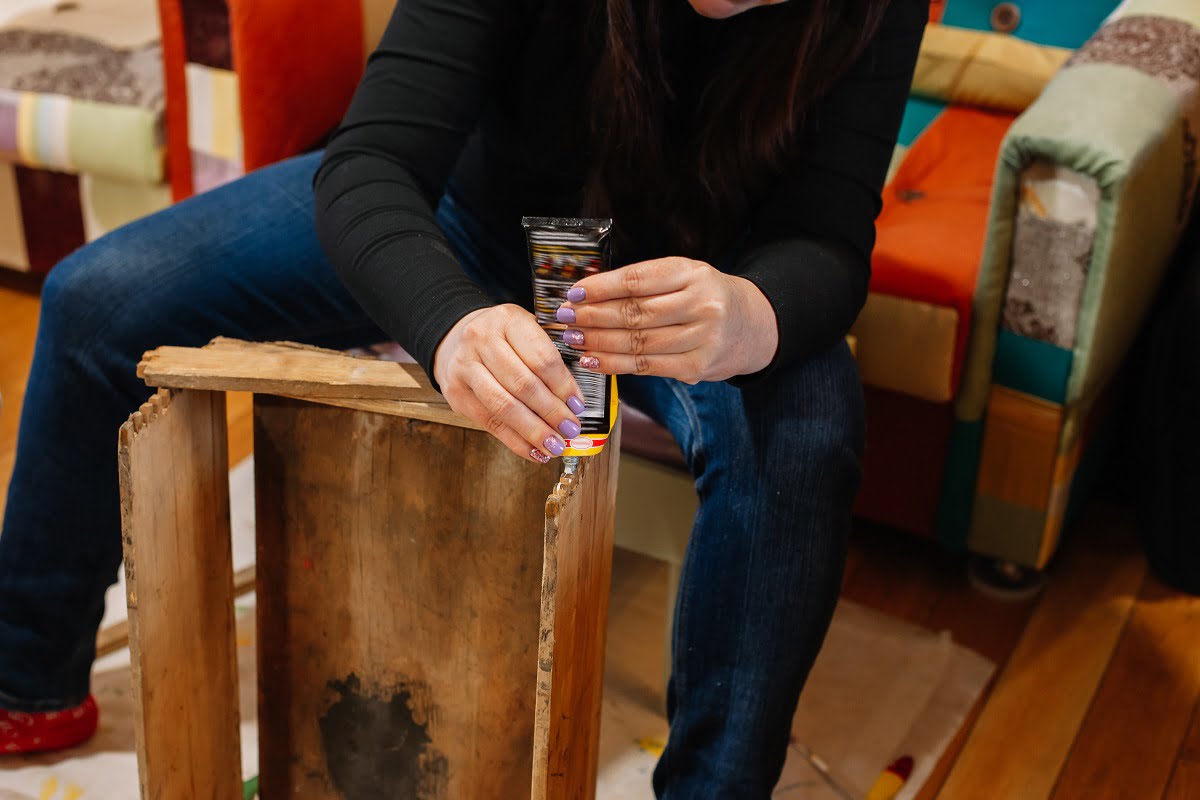 Woman with glue in hands fixing aged wooden box by gluing its peaces together in home workshop for renovation. Giving old things new life. Reuse of aged. Sustainable actions for helping planet. Steps For Using Super Glue On Wood.