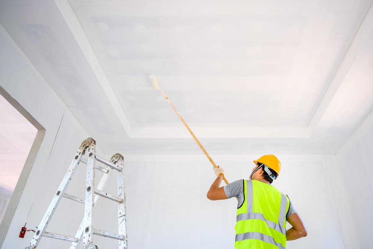 Young Asian male construction worker Work as a house painter Painting the ceiling inside the house and using a white primer paint roller on the construction site. How To Paint A Ceiling Summing It Up.