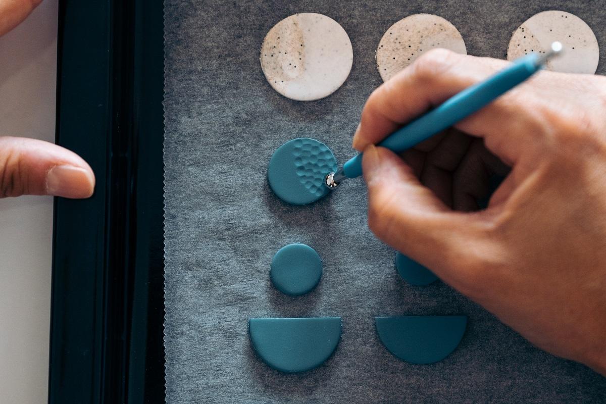 Unrecognized artisan making colorful earrings with clay and making a design. Air Drying Clay Earrings.