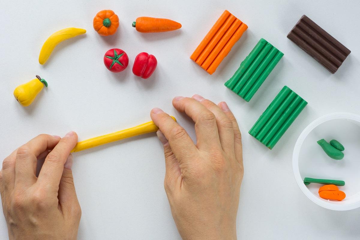 Woman hands rolling sausage from polymer clay on the white background. Best Beginner Sculpting Clay.