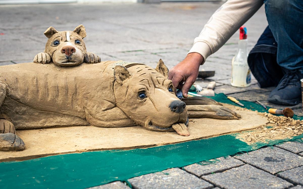 Sculpture of a dog from clay, modeling from clay in the street, a man sculpts from clay. Best Clay Modeling Ideas.