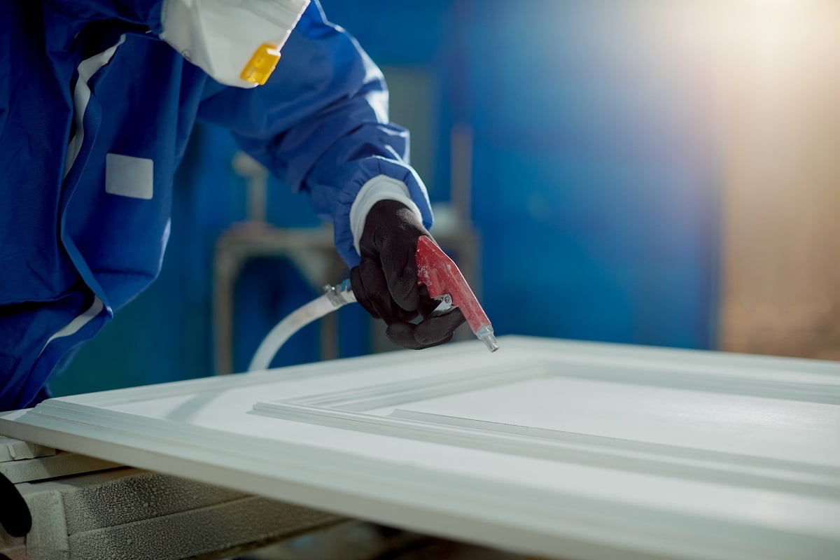 Close-up of worker spraying timber with spray gun and woodworking factory. A Guide To Painting Furniture Smoothly With Brushes.