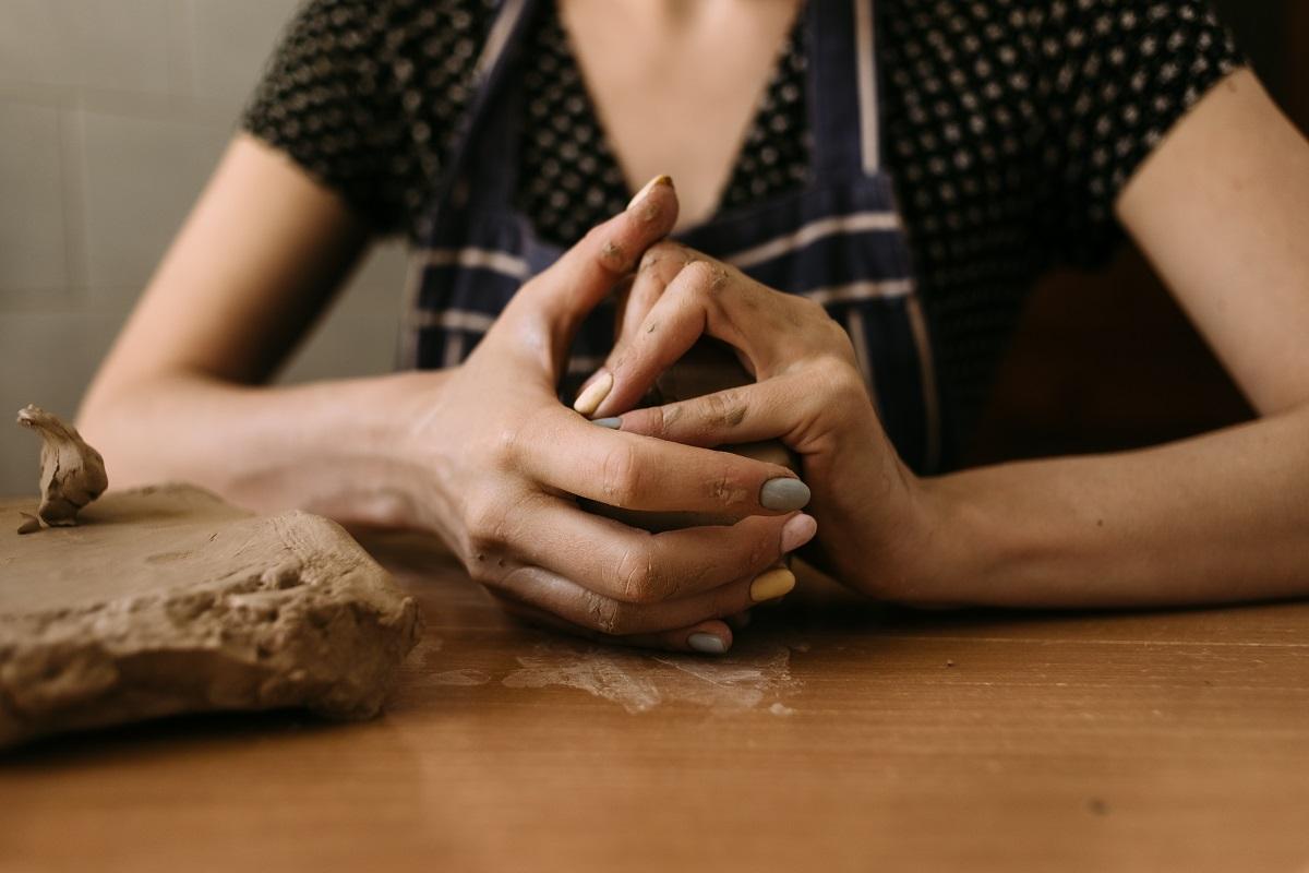close-up Hands of a woman sculptor knead clay on the table at home. Hobby clay modeling. Main Types Of Sculpting Clay.