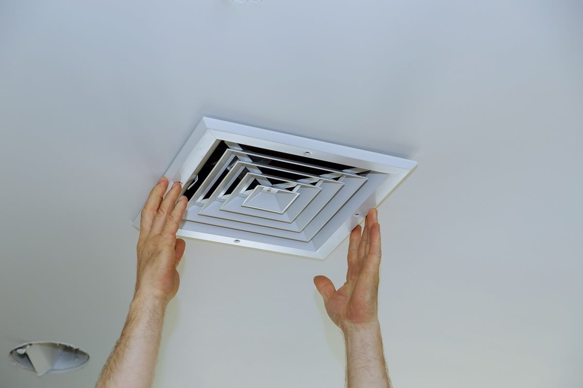 Close up man hand installing vent cover from ceiling Mounted Air Conditioner. What Are Exhaust Vents.