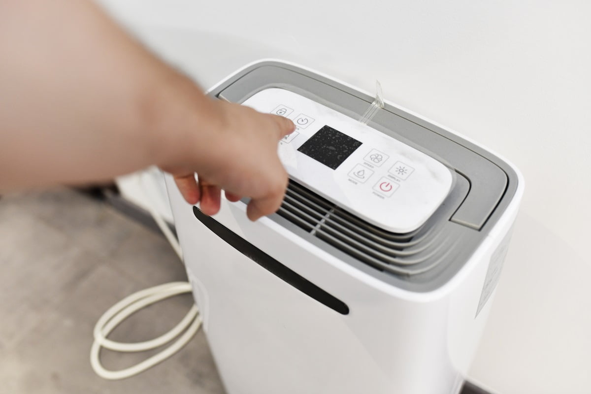 man's hand turning on a dehumidifier in the entrance of a house or office. To prevent joint pain. Most Efficient Brand Dehumidifier For Bedroom Final Words .