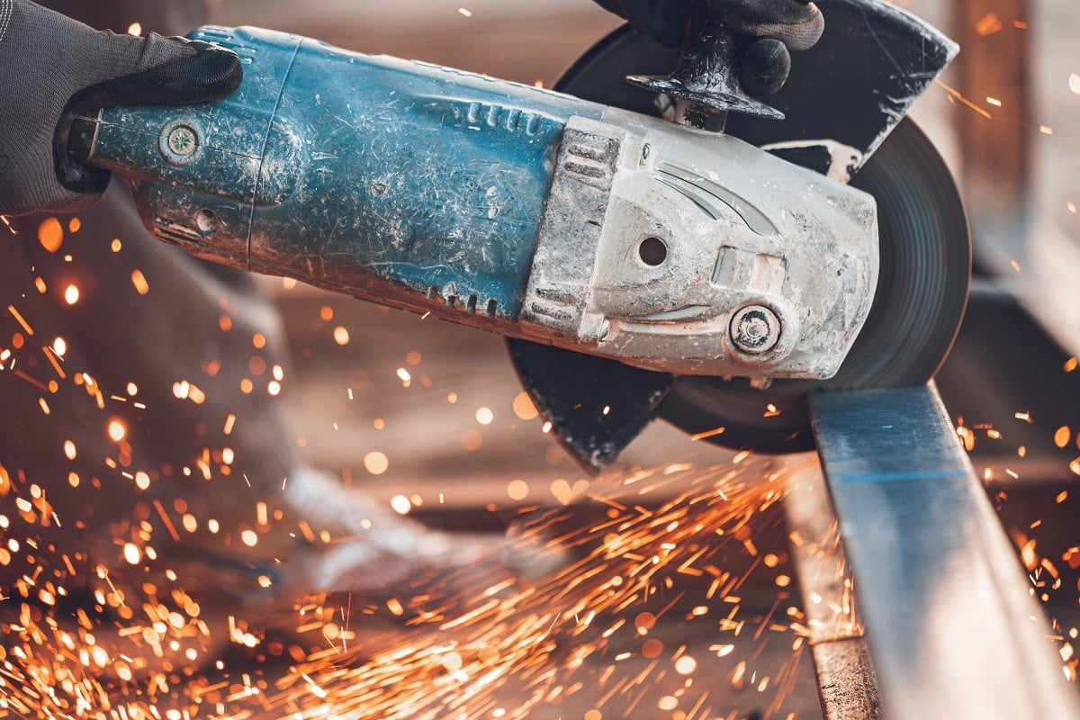 Construction worker using Angle Grinder cutting Metal at construction site. What's An Angle Grinder.