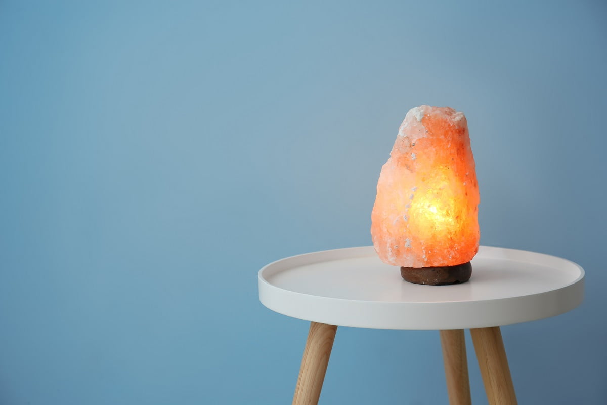 Himalayan salt lamp on table against color background. Himalayan Salt Lamps Buying Guide