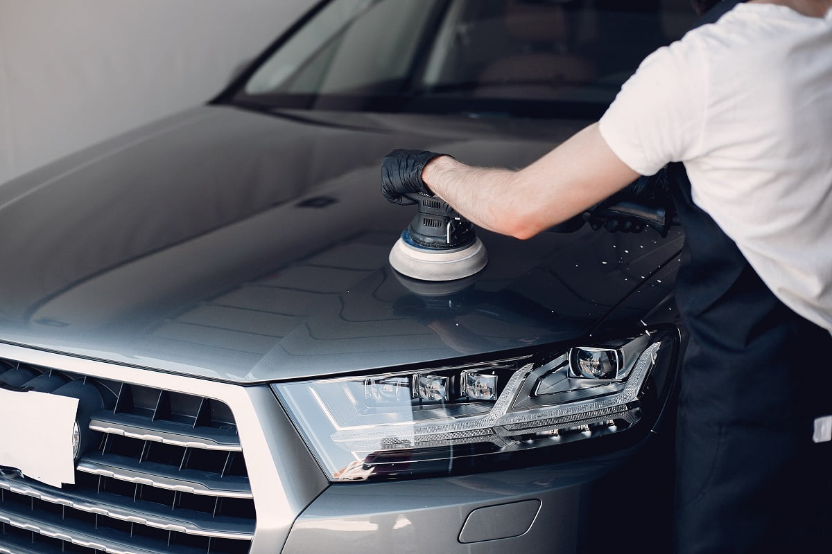 Man in a garage. Worker polish a car. What Are Angle Grinders And Polishers.