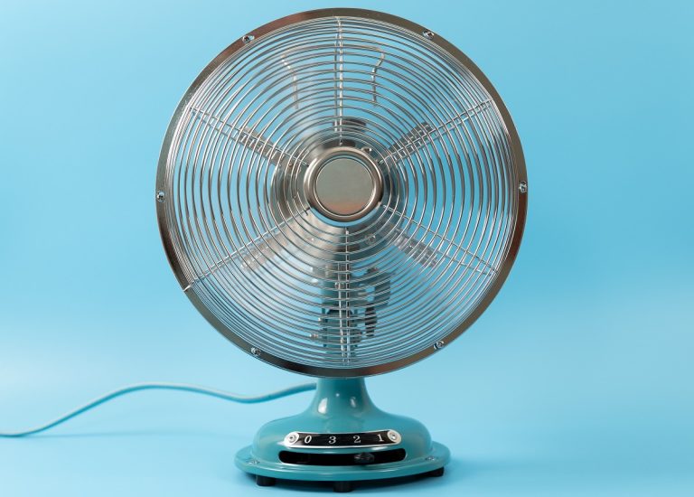 Retro vintage tabletop fan isolated on a blue background. Why Is My Fan Blowing Hot Air.
