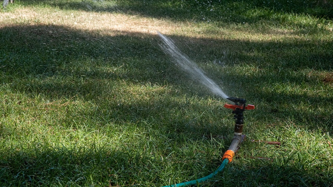 Lawn water sprinkler spraying water on garden lawn on hot summer day. Automatic watering lawns. How To Install An Impact Sprinkler Conclusion.