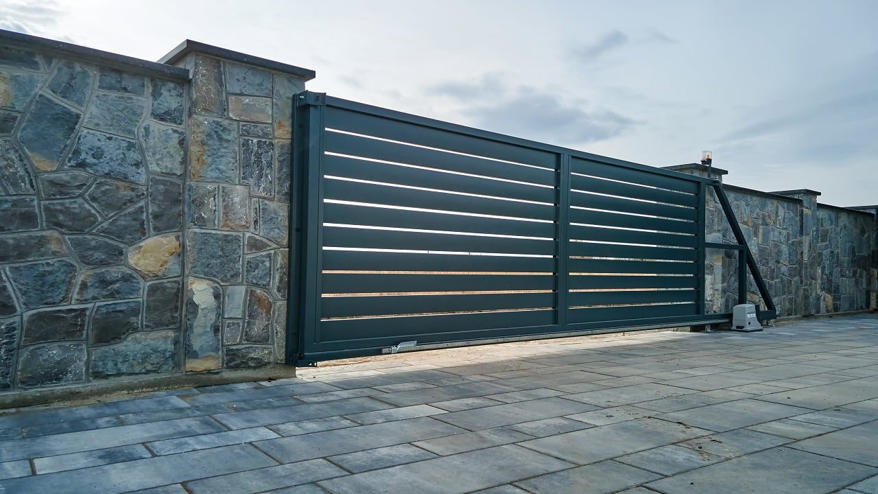 Wide automatic sliding gate with remote control installed in high stone fense wall. Security and protection concept. How To Increase The Efficiency Of A Sliding Gate Final Words.