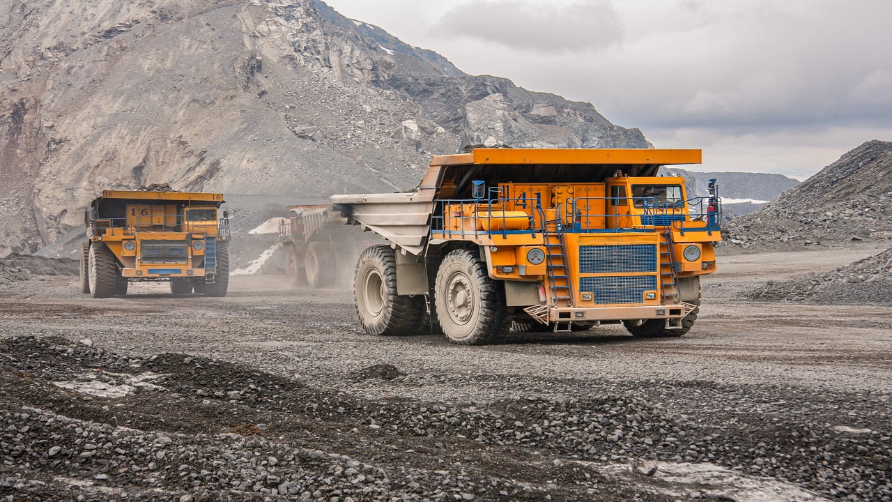 Giant dump trucks are working in the mine for the production of apatite in the Murmansk region carrying rock. Extraction of minerals in the harsh highlands. Off-highway Trucks.